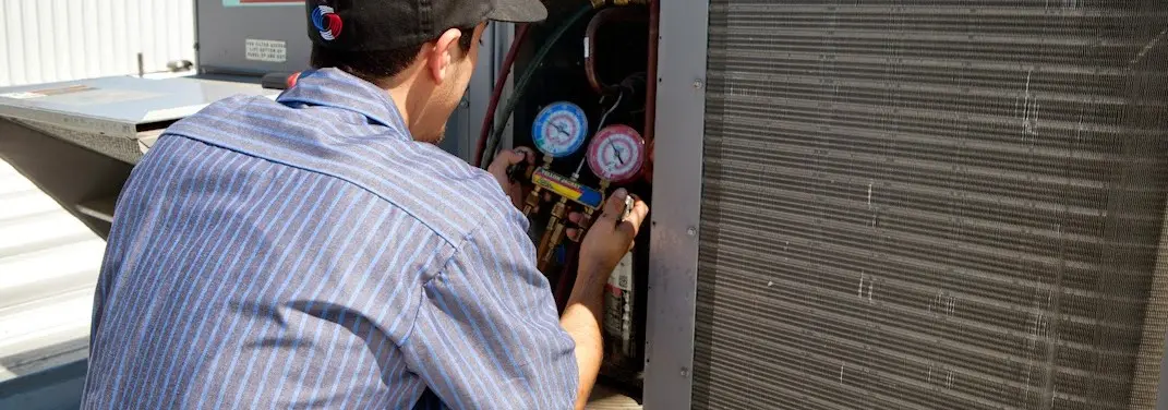 HVAC technician servicing a condenser unit in Lumberton