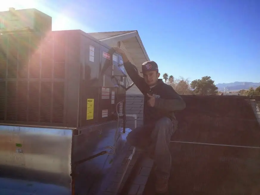 HVAC technician performing AC Tune-Up on a rooftop unit in Lumberton